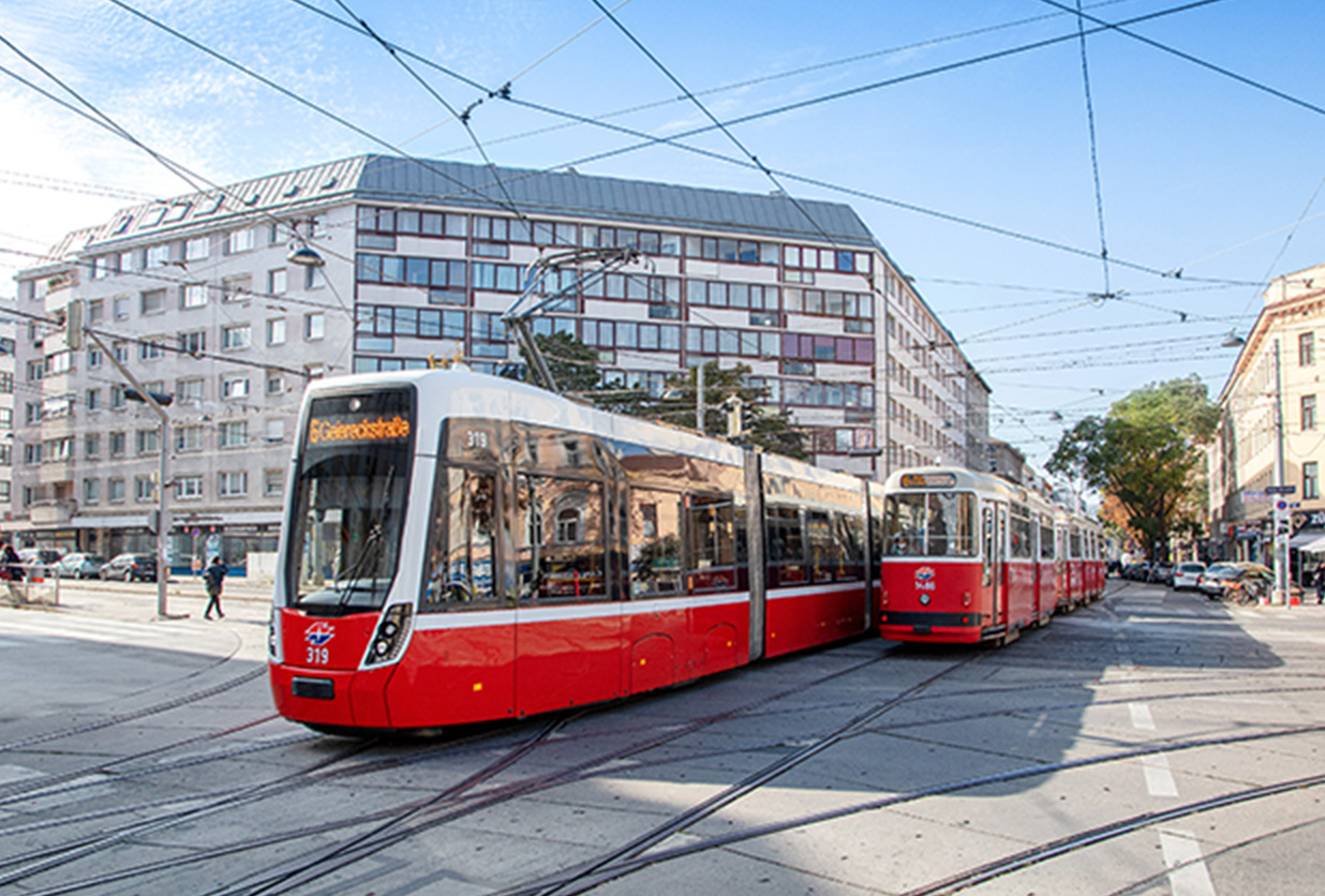 Zwei Straßenbahnen der Wiener Linien überqueren eine Kreuzung.