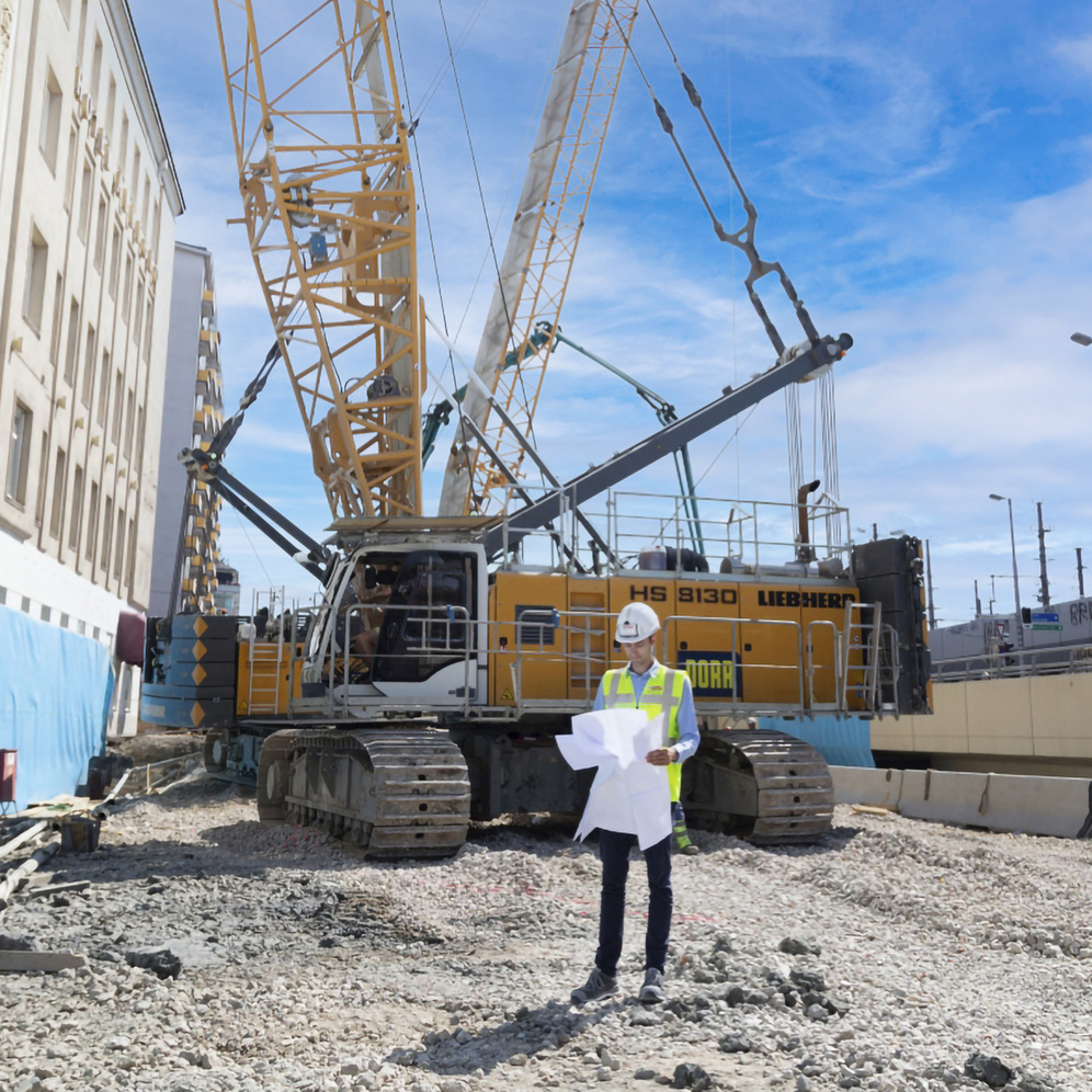 A construction site with a large crane and an employee wearing a hard hat. C: Johannes Zinner