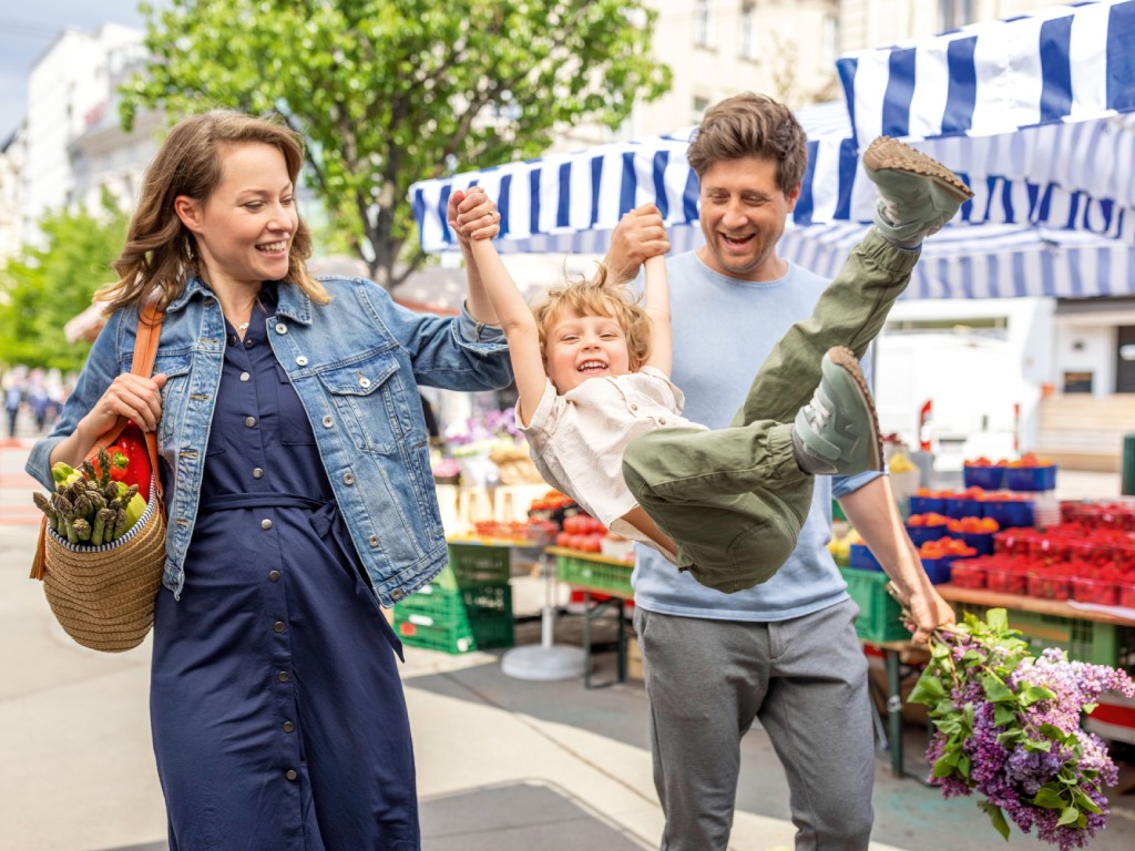 Eine junge Familie hat Spaß auf einem Wochenmarkt. Foto: Wiener Stadtwerke/Severin Wurnig
