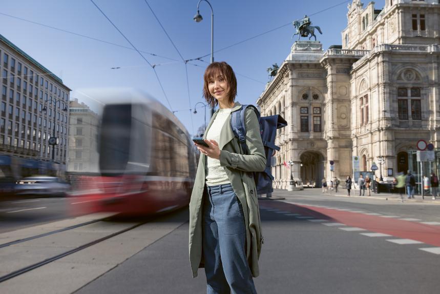 Junge Frau benutzt ein Mobiltelefon vor der Wiener Staatsoper